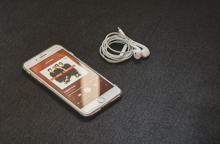Smartphone tocando música ao lado de fones de ouvido brancos